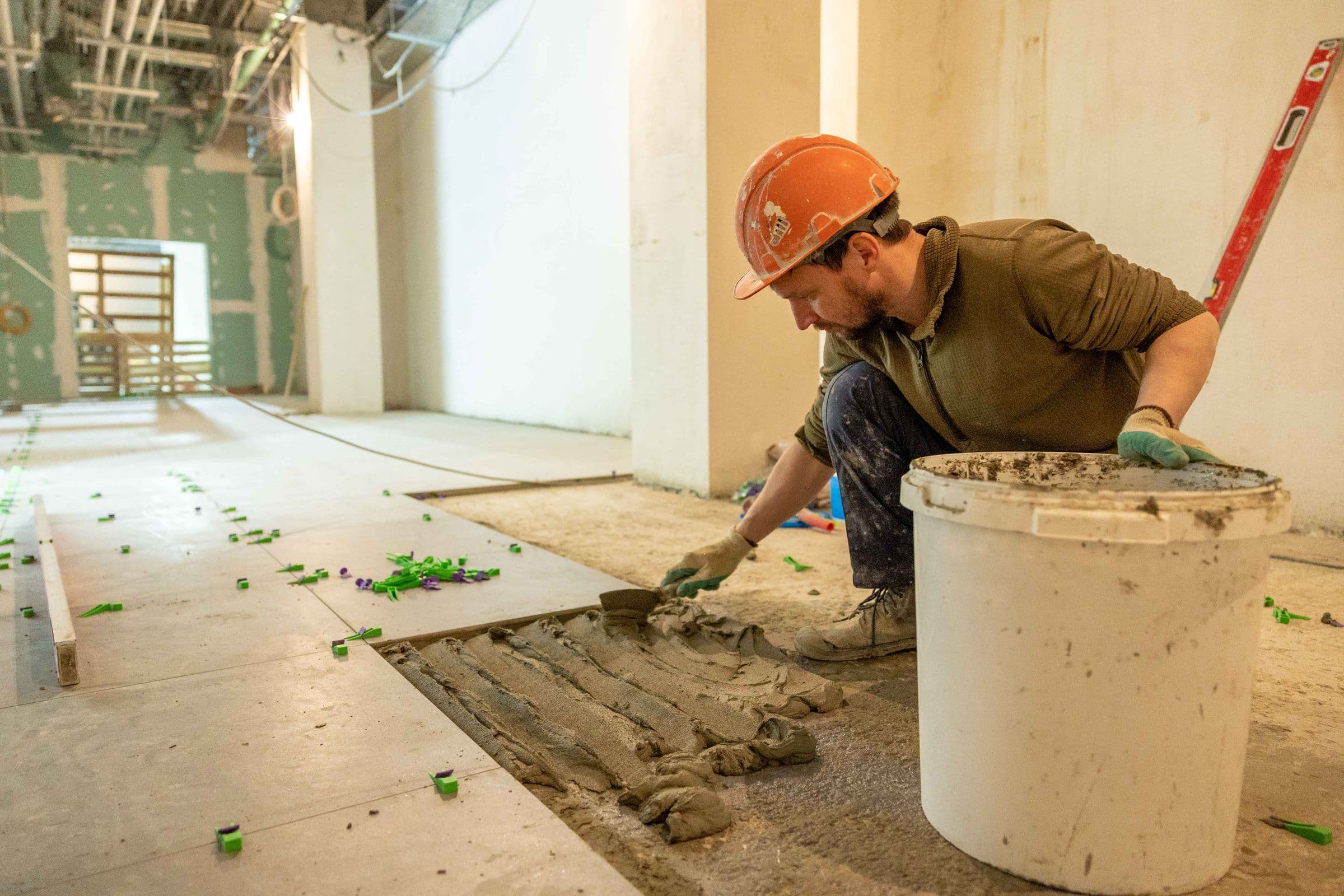Tiler laying floor tiles on a renovation site